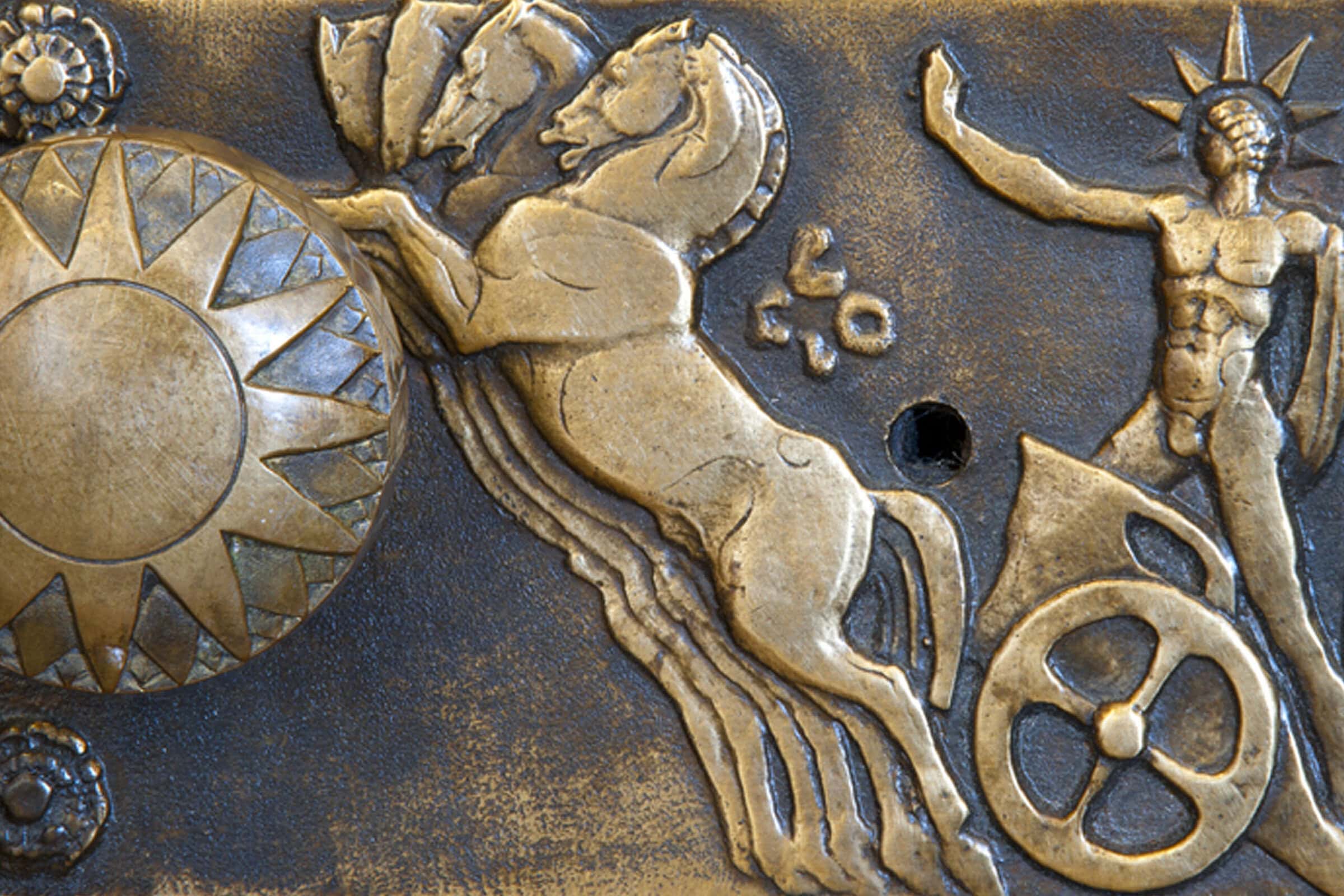 A bronze plaque featuring a horse and a sun, symbolizing strength and vitality.
