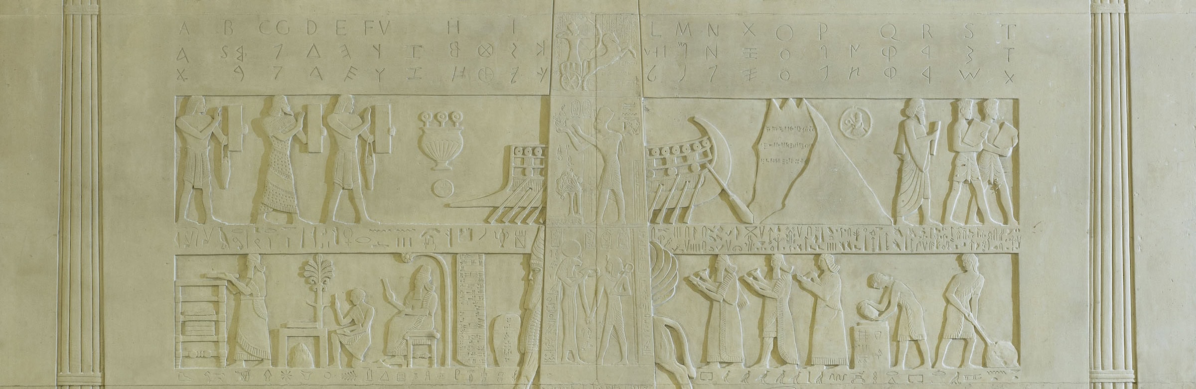 A large white wall with a large picture of people, featuring Ancient Egyptian symbols.
