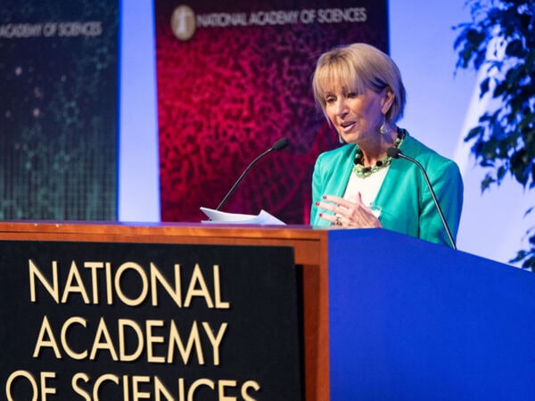 A woman delivering a speech at the National Academy of Sciences, addressing a distinguished audience.