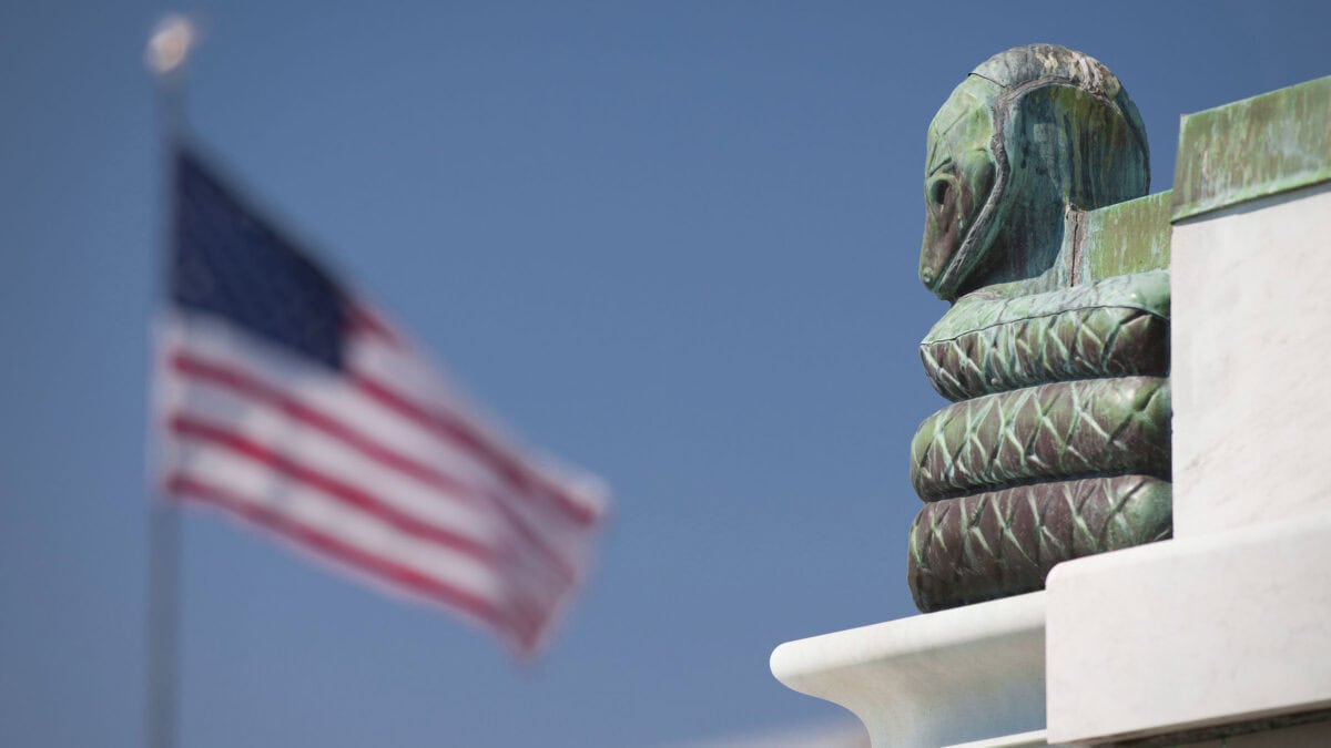 Snake statue on building with American flag in background.